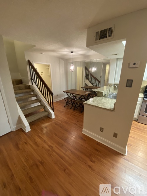 A living room with a staircase and a dining table.