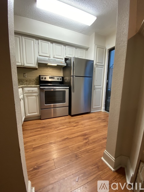 A kitchen with a stove top oven, refrigerator, and cabinets.
