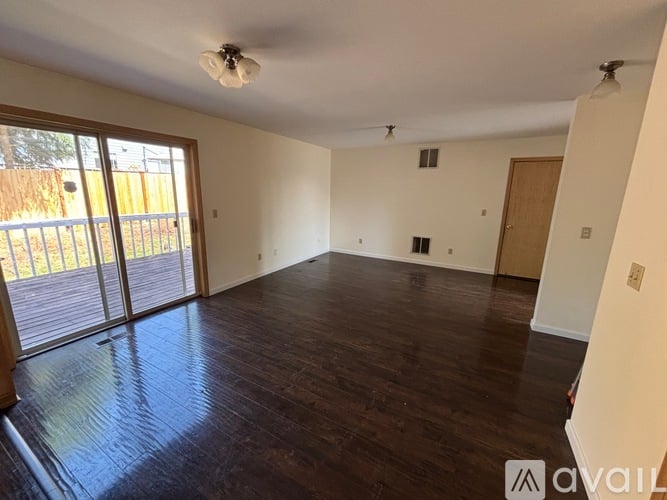 A spacious room with wooden floors and sliding glass doors.