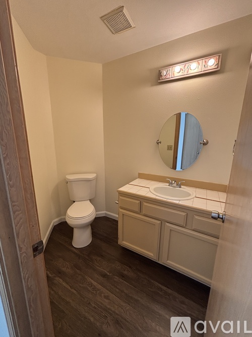 A bathroom with a toilet, sink, and mirror.