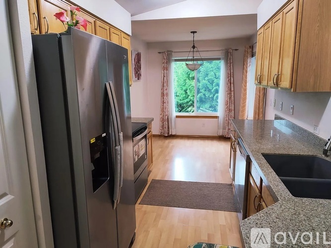 A kitchen with a refrigerator, sink, and cabinets.