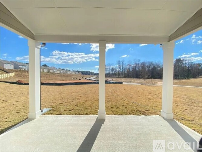 A covered patio area with a view of a field and buildings in the distance.