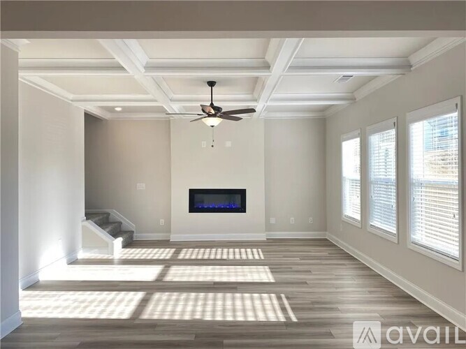 A spacious living room with a television and a staircase.