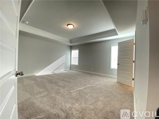A spacious room with a carpeted floor and white walls.