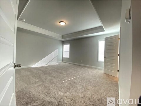 A spacious room with a carpeted floor and white walls.