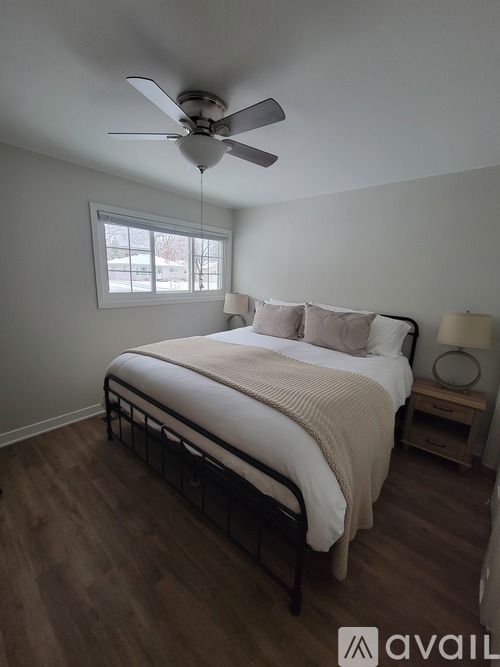 A bedroom with a bed, nightstand, and window.