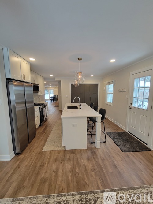 A kitchen with a refrigerator, sink, and a dining table with chairs.
