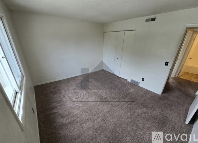 A room with a carpeted floor and a window on the left side.
