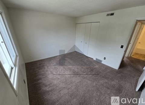 A room with a carpeted floor and a window on the left side.