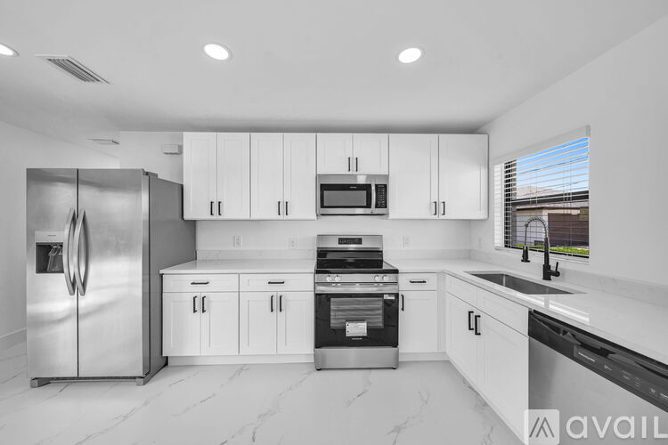 A modern kitchen with white cabinets and stainless steel appliances.