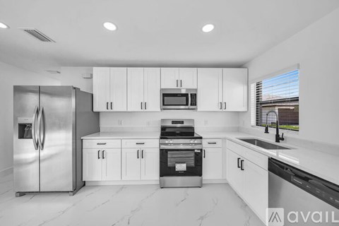 A modern kitchen with white cabinets and stainless steel appliances.