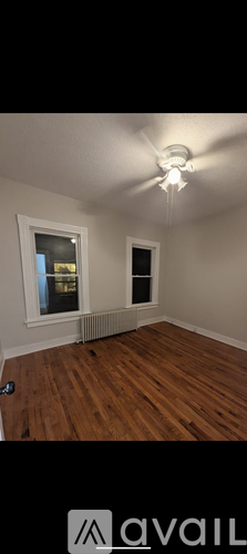 A room with wooden floors and a window with a view of a building outside.
