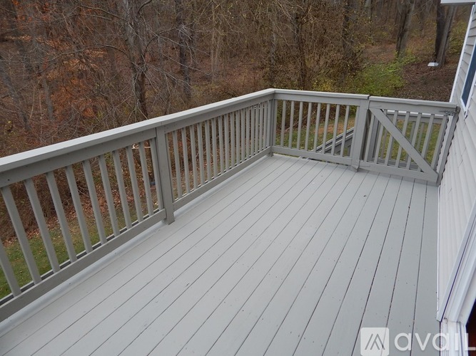 A deck with a railing and a view of trees.