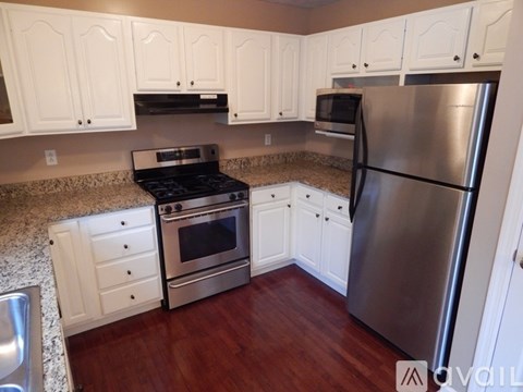 A kitchen with white cabinets and a stainless steel refrigerator.