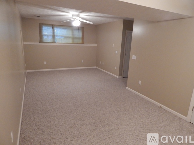 A spacious room with a carpeted floor and a ceiling fan.