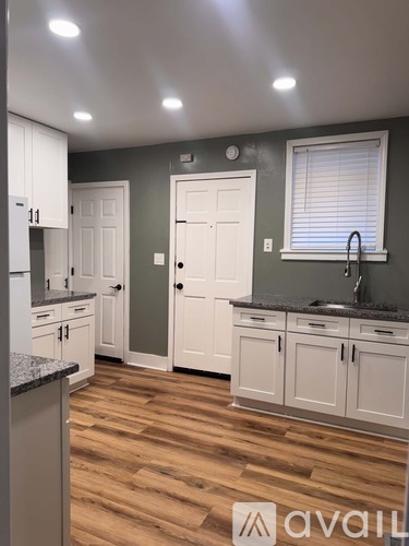 A kitchen with white cabinets and a wooden floor.
