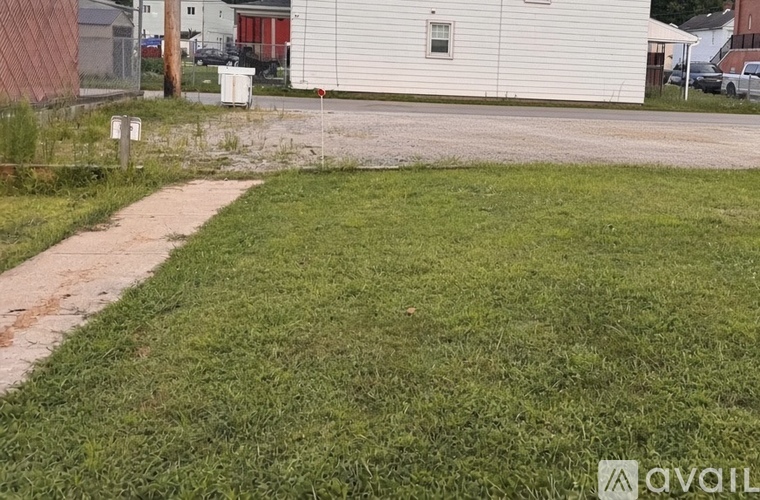A grassy area with a concrete path leading to a white building.