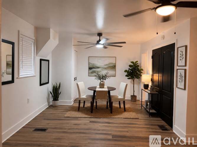 A dining room with a table set for two and a ceiling fan.