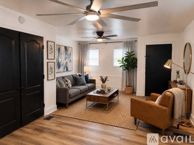 A living room with a brown sofa, a coffee table, and a ceiling fan.