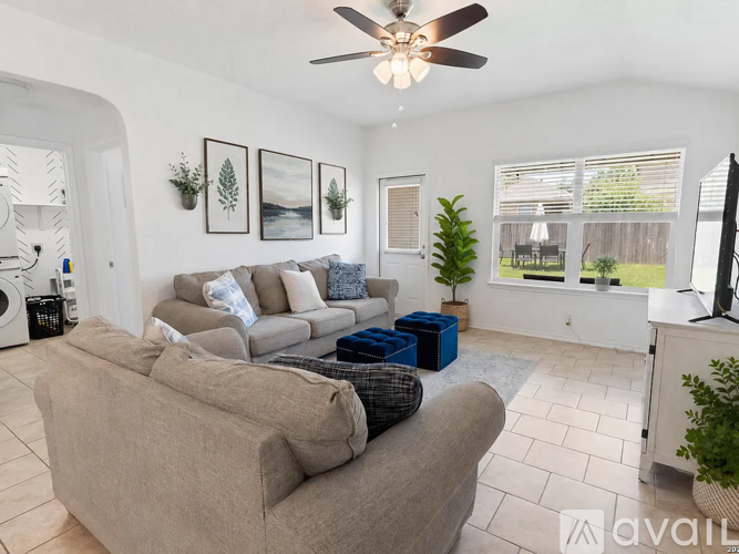 A living room with a beige couch and a ceiling fan.