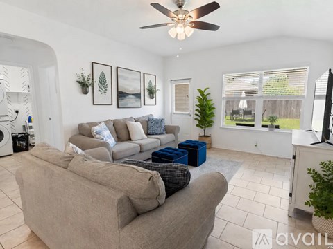 A living room with a beige couch and a ceiling fan.