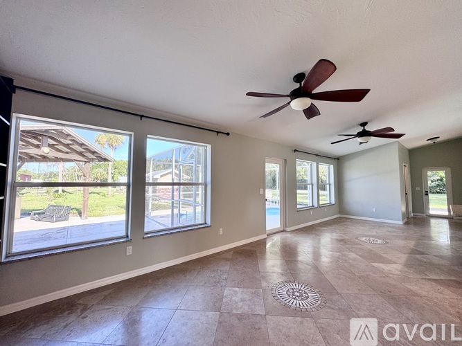 A spacious room with a ceiling fan and large windows.