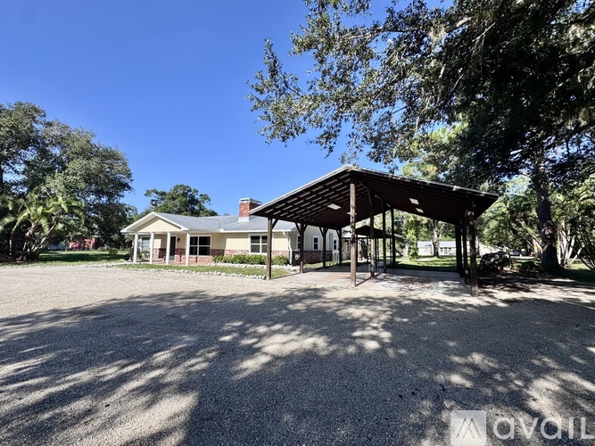 A house with a covered patio is surrounded by trees.