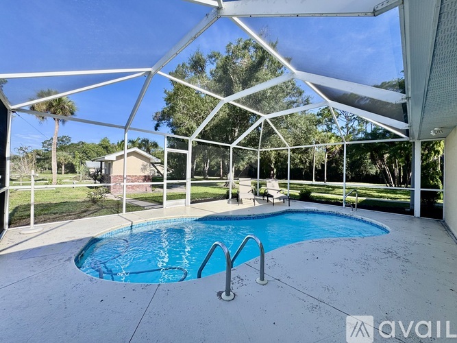 A pool enclosed by a white metal frame with a clear sky in the background.