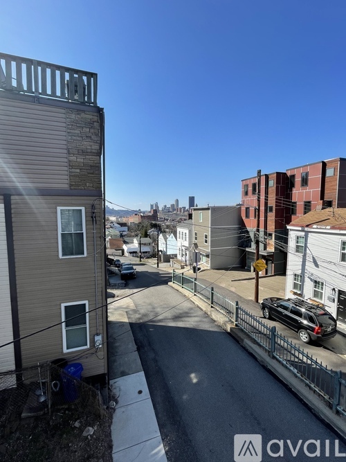 A street view of a residential area with apartment buildings and cars parked on the side of the road.