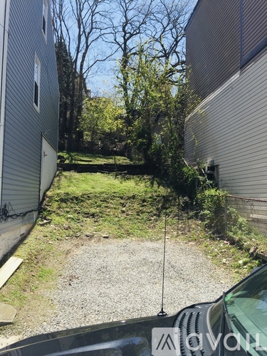 A gravel area between two buildings with a car parked in front.