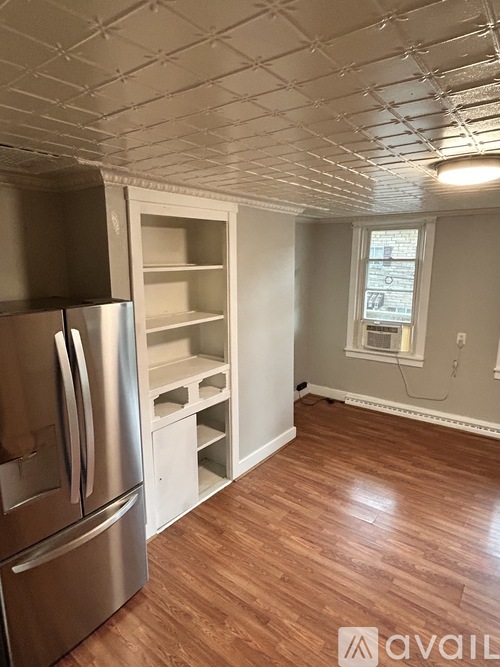 A kitchen with a stainless steel refrigerator and wooden flooring.