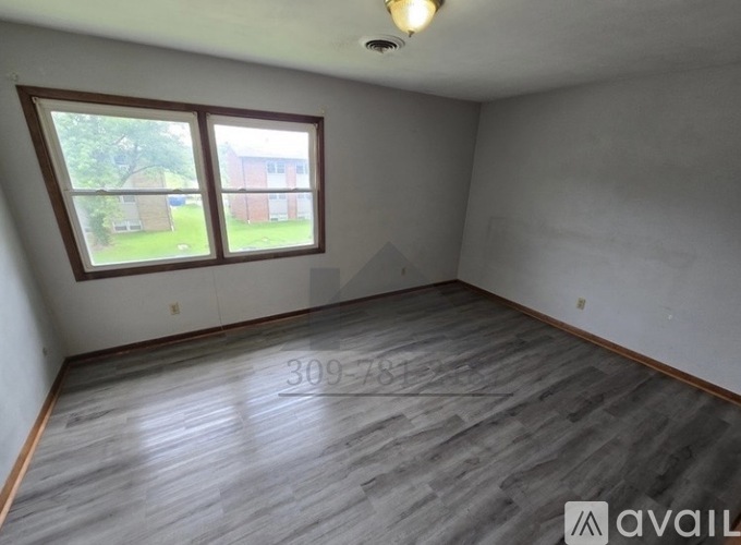 A room with a large window and wooden flooring is available for rent.