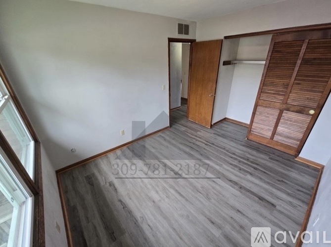 A room with a wooden floor and a door on the left side.