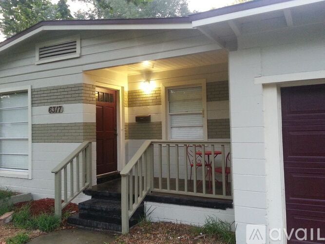A small white house with a red door and a sign that reads 6317.
