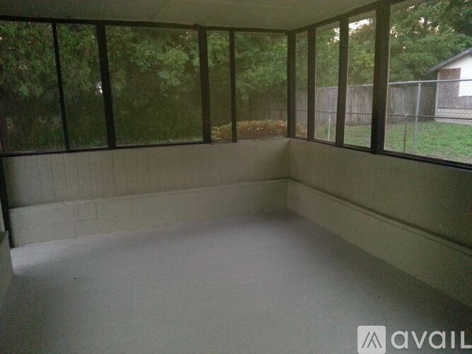 A room with large windows and a view of a fence and trees.