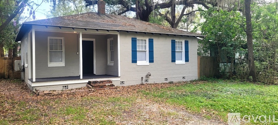 A small house with a porch and a fence in front of it.