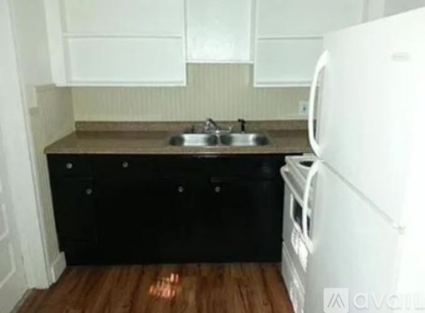 A kitchen with a white fridge and black drawers.