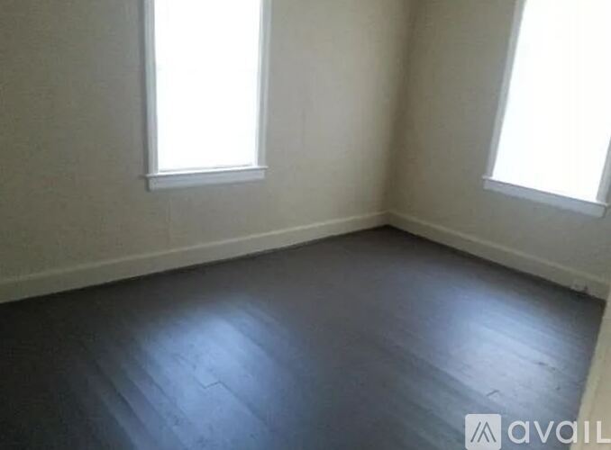 A room with two windows and wooden flooring.