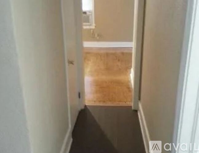 A hallway with a wooden floor and white walls.