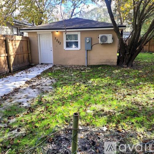 A small house with a brown fence and a tree in front.