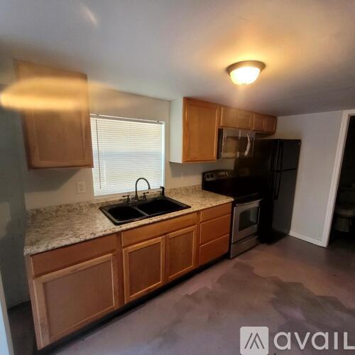 A kitchen with wooden cabinets and a black refrigerator.