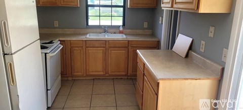 A kitchen with a white refrigerator and wooden cabinets.