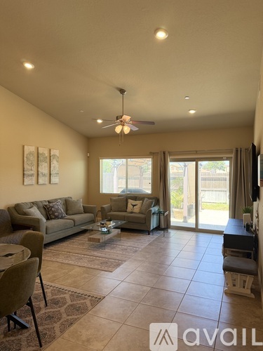 A living room with a couch, chairs, and a ceiling fan.