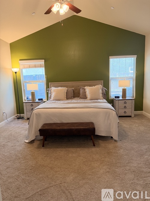 A bedroom with a bed, nightstands, and a window.