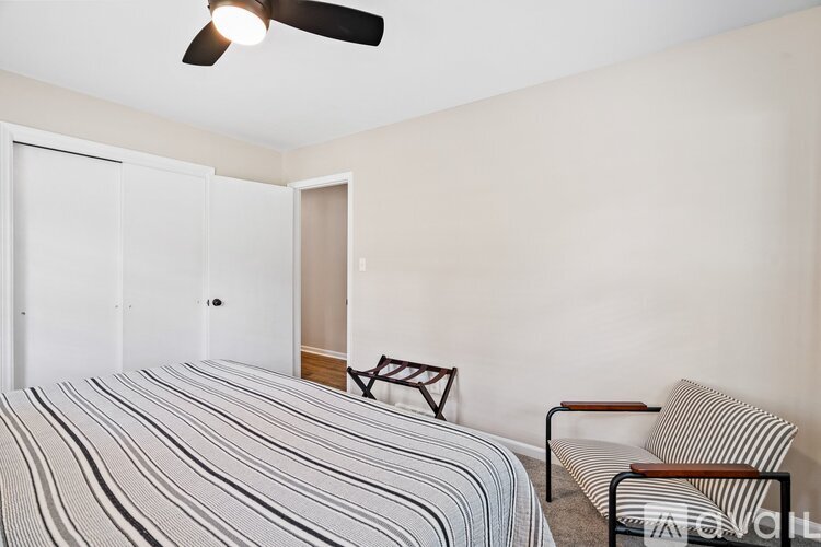 A bedroom with a bed, chair, and ceiling fan.