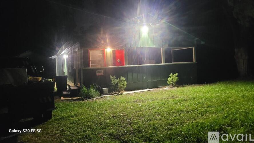 A building with a red door is illuminated by a bright light at night.