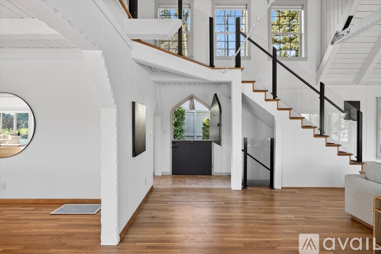 A spacious interior of a house with a staircase and a large window.