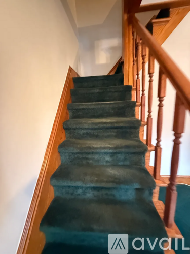 A staircase with a green carpet and wooden balusters.