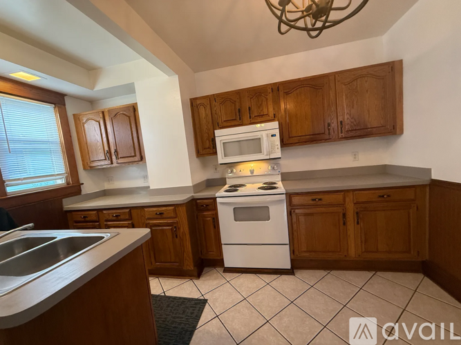 A kitchen with wooden cabinets and a white stove top oven.