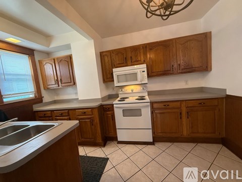 A kitchen with wooden cabinets and a white stove top oven.
